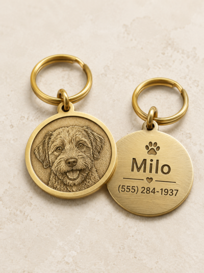 Custom engraved brass pet tag showing a detailed dog portrait on the front and personalized pet name and phone number on the back