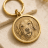 Close-up of a custom engraved brass pet tag with a detailed dog portrait engraving, polished round edge, and gold keyring