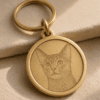 Close-up of a custom engraved brass pet tag with a detailed cat portrait engraving, round polished edge, and warm brushed brass finish