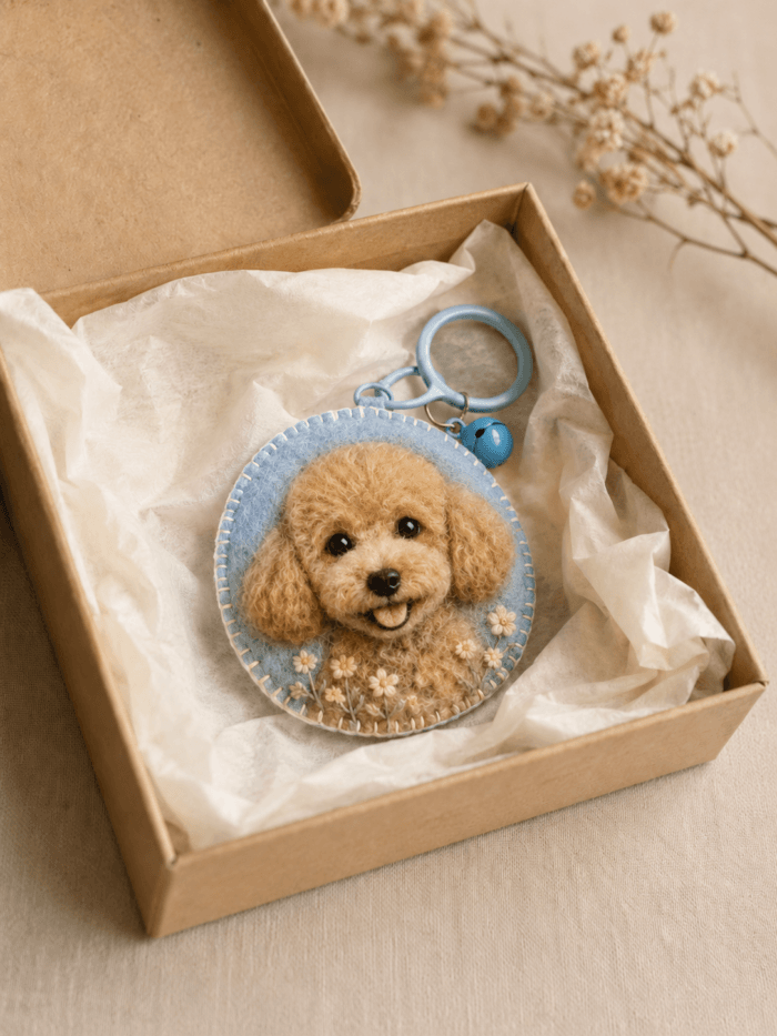 Custom dog portrait felt charm presented in a kraft gift box with tissue paper, handmade wool felt texture, floral embroidery, and blue keyring