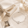 Woman wearing a gold custom pet portrait bracelet beside a black and white cat photo